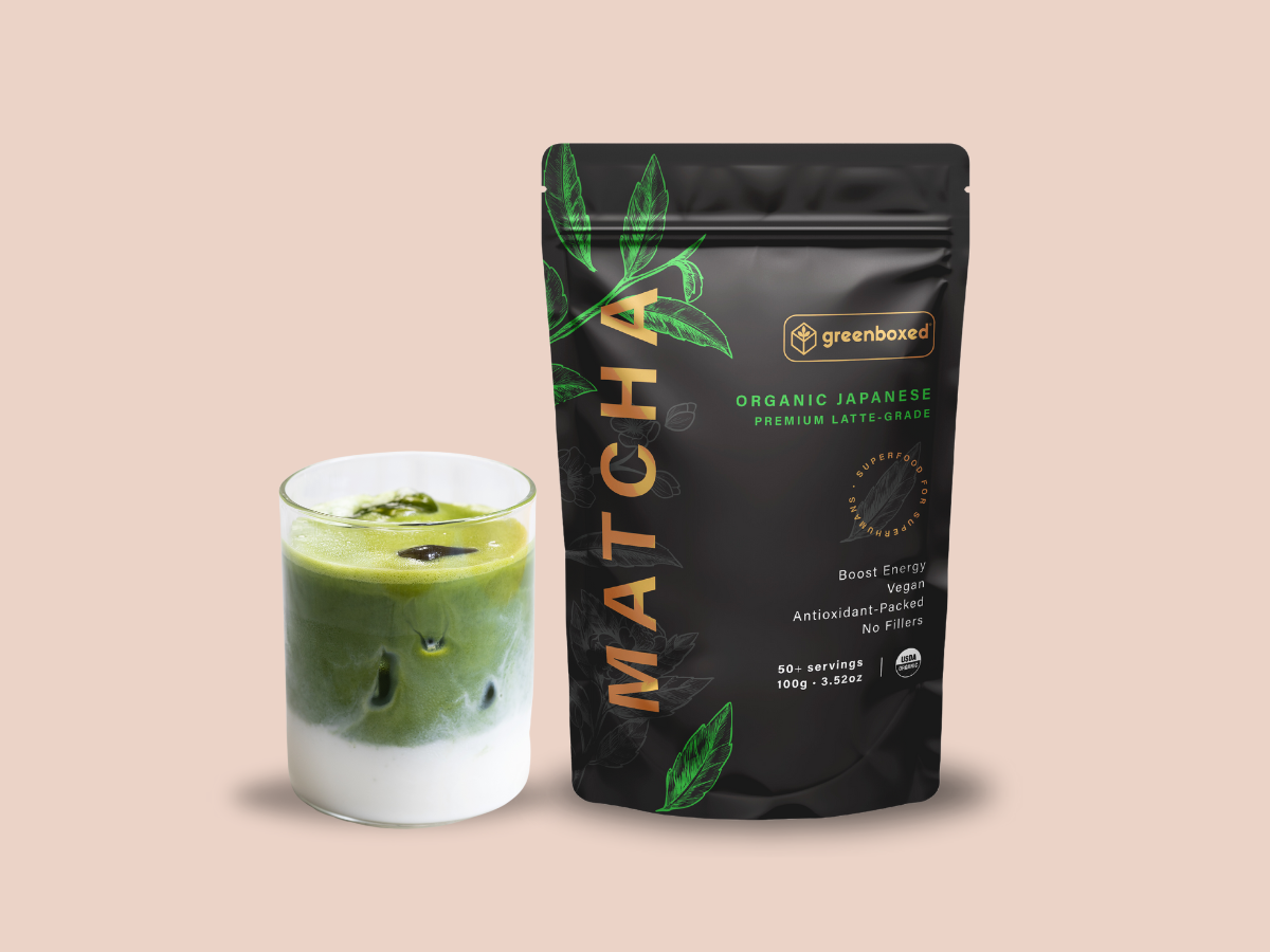 A 100g / 3.52oz bag with an iced matcha latte. A premium latte grade matcha black pouch. The pouch is black and has green matcha leaves, as decoration. The background of the image is pink. The image has a text stating " Best matcha for daily lattes . Barista approved and created for you to make at home"