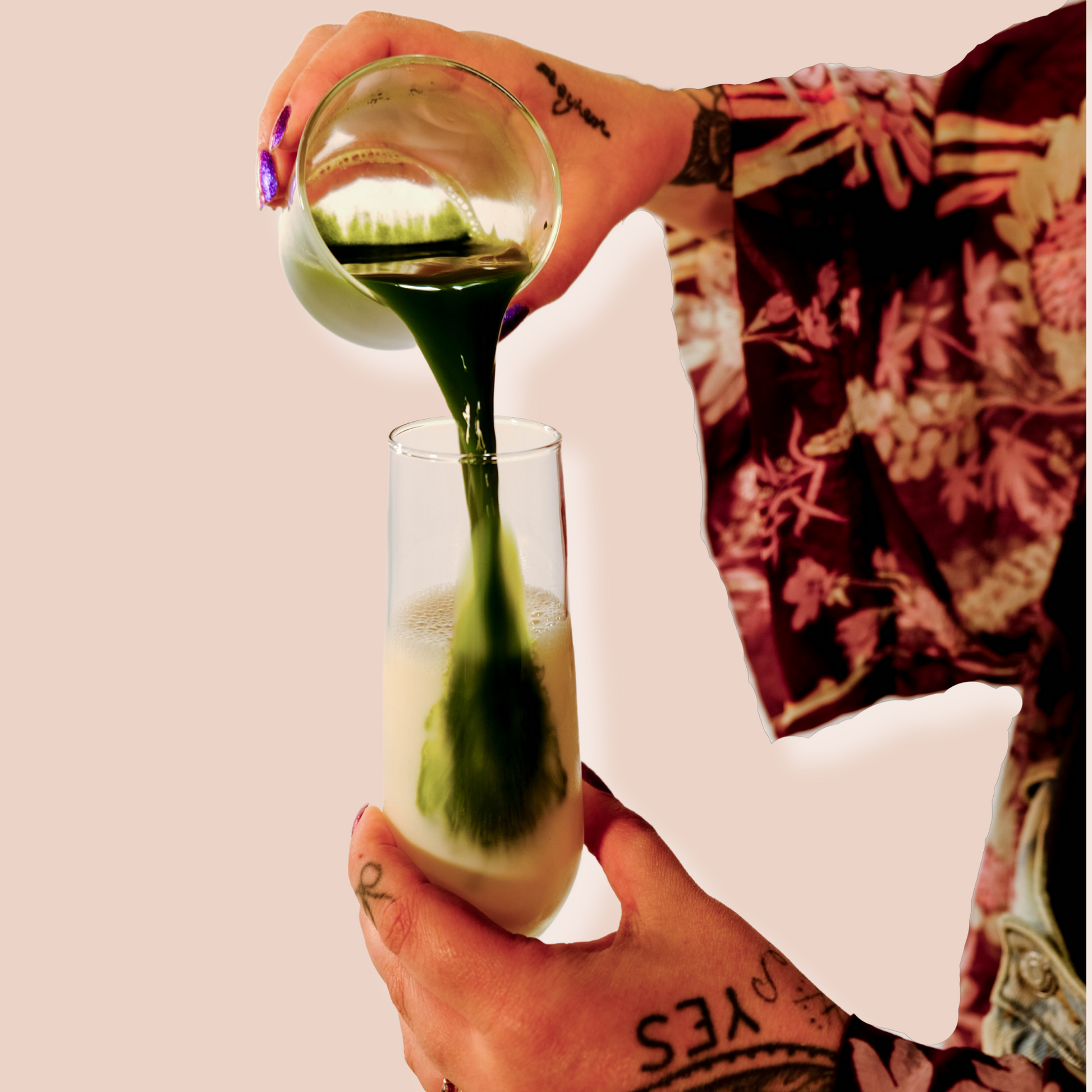 Women's hand pouring matcha shot to plant based milk. The matcha shot has a deep and vibrant green color. The woman is using Greenboxed matcha powder 